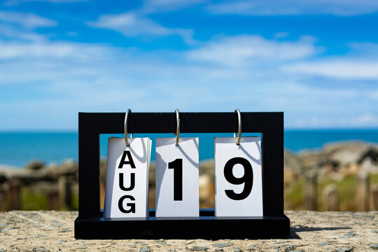 Aug 19 calendar date text on wooden frame with blurred background of ocean.