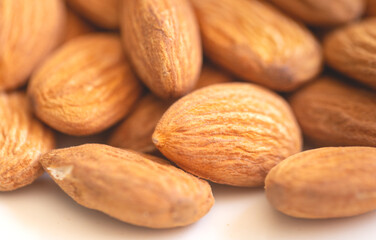 Amêndoas colocadas em um prato branco em fotografia macro. Oleaginosa rica em antioxidantes,...