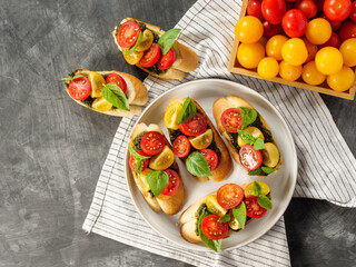 Italian antipasti bruschetta with tomato, basil and pesto on a gray table. Copy space.