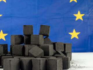 Black cubes of coal on the background of the EU flag. Concept Coal shortage in Europe.