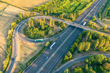 Highway from a bird's eye view. As the sun goes down, the sun's rays create beautiful long shadows on the ground. Yellow trees and surrounding farmland