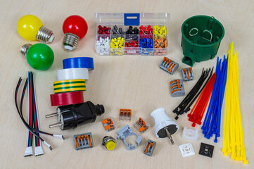 Electrical components and parts of different colors on a plywood background.