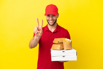 pizza delivery man picking up pizza boxes and burgers over isolated background smiling and showing...