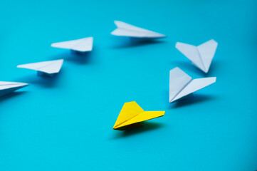 Yellow paper plane origami leading white planes on blue background. Leadership skills concept