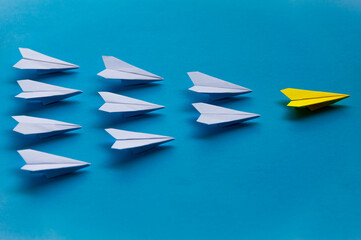 Naklejka premium Yellow paper plane origami leading white planes on blue background. Leadership skills concept