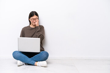 Young woman with a laptop sitting on the floor laughing