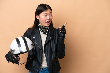 Fototapeta na wymiar Young Chinese woman with a motorcycle helmet isolated on beige background intending to realizes the solution while lifting a finger up
