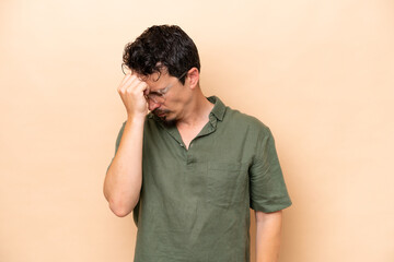 Young caucasian man isolated on beige background with headache