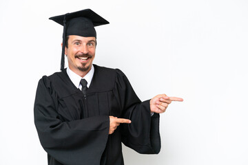 Young university graduate man isolated on white background surprised and pointing side