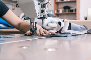 The seamstress sews at the sewing machine, threads the fabric. Women's hands