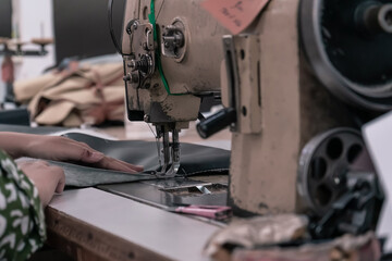 The seamstress sews on an old sewing machine, threads the fabric. Women's hands