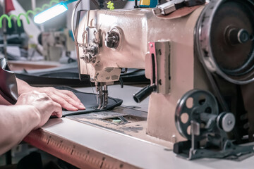 The seamstress sews on an old sewing machine, threads the fabric. Women's hands