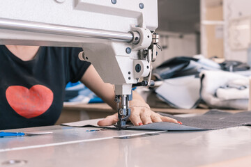 The seamstress sews at the sewing machine, threads the fabric. Women's hands