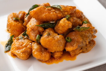 Crispy fried dori fish coated with salted egg plated on a white plate