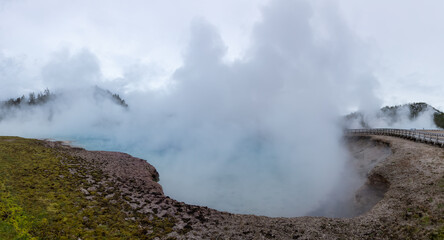 Hot spring Geyser with colorful water in American Landscape. Cloudy Sky. Yellowstone National Park, Wyoming, United States. Nature Background Panorama