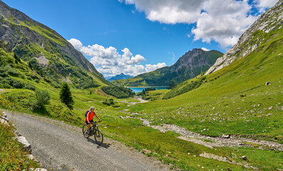 Fototapeta na wymiar active senior woman, riding her electric mountain bike at Spuller Lake in the Arlberg area near the famous village of Lech, Tirol, Austrian Alps