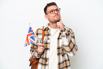 Young hispanic man holding an United Kingdom flag isolated on white background having doubts while looking up