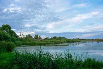 duckweed covered lake kiovo, moscow region, russia, Orthodox church on the shore overgrown with reeds at summer evening
