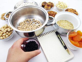     Traditional Turkish dessert ashura ingredients.A hand holding currants              