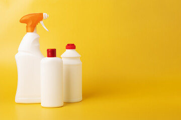 bottles with cleaning detergents and spray on yellow background, professional cleaning service