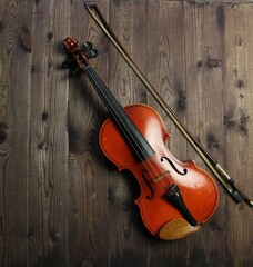 Fototapeta na wymiar violin and bow on brown wooden background