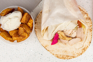 Shawarma sandwich fresh roll of, Grilled Chicken and potato wedges wrap with white sauce on white table background