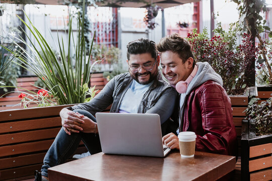 Hispanic Homosexual Male Couple Having A Good Time Surfing On Their Computer In A Latin American City