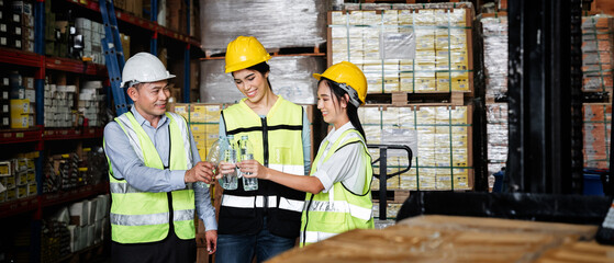 Warehouse workers relax and drink water from bottles in warehouse.