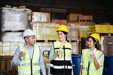 Warehouse workers relax and drink water from bottles in warehouse.