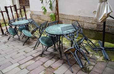 Empty cafe terrace seating with round vintage metal tables and chairs waiting for visitors