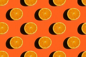 Seamless pattern of a flat layed fresh ripe orange fruit cut in half on a bright orange background
