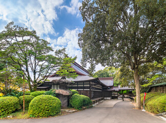 kyushu, japan - december 08 2021: Exterior corridor in the back of the Miyajidake Shrine of Fukuoka passing through its backyard adorned with rounded niwaki shrubs and a big Nozura stone lantern.