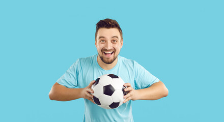 Portrait of overjoyed young man isolated on blue studio background hold ball support football team....
