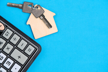 Calculator and keychain with house keys blue background.Concept mortgages, buying and renting housing.