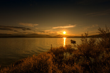 Krajobraz wodny. Widok na jezioro i zachód słońca. Piękny zachód słońca nad jeziorem ze starą łodzią i bezchmurnym niebem w tle, Polska	 - obrazy, fototapety, plakaty