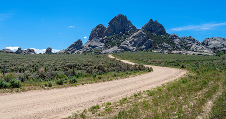 Panorama of a dirt road leading to granite outcroppings at the City of Rocks National Reserve,...
