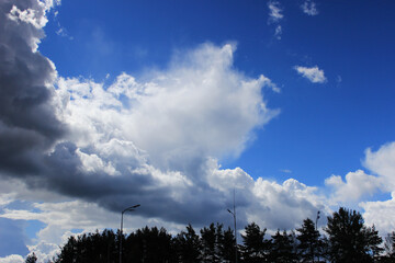 large white cloud and blurry white strokes against a bright blue sky. The cumulus nature of the clouds is a harbinger of a downpour