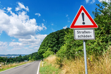 Verkehrszeichen Straßenschild Warnschild Straßenschäden an Landstraße mit Landschaft im Sommer