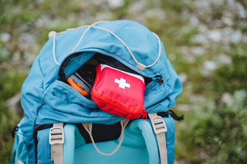 First aid kit for travel is in the pocket of the backpack, emergency assistance in case of injury on the trip a set of medicines in a red bag, the concept of a first-aid kit medical