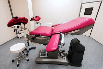 modern, multifunctional pink gynecological chair in the center of the room - obrazy, fototapety, plakaty