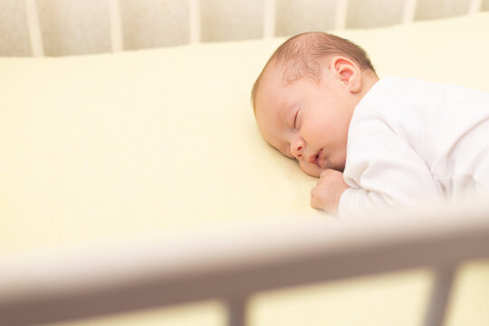 The baby sleeps in the copy space crib . Advertising of children's goods. Illustrating children's articles. A small child. A newborn.