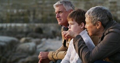 Boy bonding and sitting with his grandparents at the beach while discussing what they see. Building a natural relationship with your grand child. Seniors enjoy spending quality time with family.