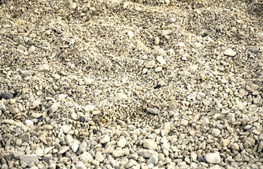 Pebble surface on the sea beach with many pebbles of various sizes