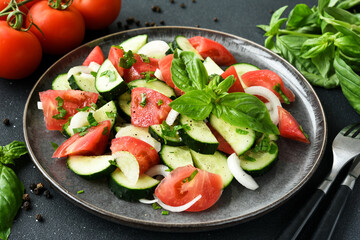 Vegetable salad with tomatoes, cucumber and onion on a dark concrete background.