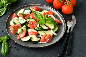 Vegetable salad with tomatoes, cucumber and onion on a dark concrete background.
