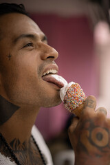 Young handsome mexican tattooed man eating ice cream in a waffle cone.