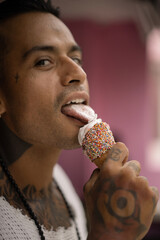 Young handsome mexican tattooed man eating ice cream in a waffle cone.