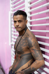 Fototapeta na wymiar Young handsome sexy mexican tattooed man against a pink wall.