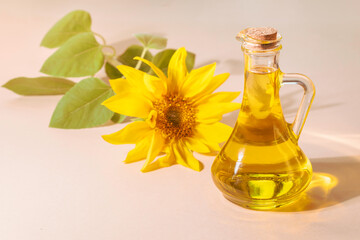 Bottle of sunflower oil and sunflower flowers on a beige background.Space for text