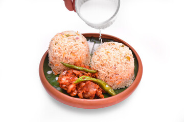 Pittu, a Sri Lankan meal with seeni sambol and coconut milk on a clay pot and a banana leaf 